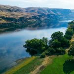 A scenic river winds through Asotin, WA, bordered by lush trees and rolling hills.